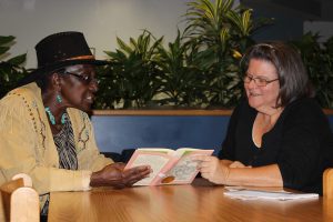 A photo of A former student and tutor in the SSC Adult Volunteer Literacy Tutoring Program read together.