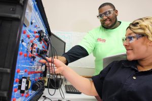 A photo of former South Suburban College students adjust an AC/DC electrical system.