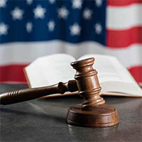 A gavel in front of a book and American flag.